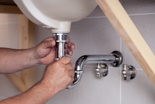 Plombier installant un lavabo dans une salle de bains neuve du Val d'Oise